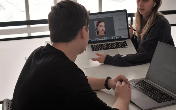 Man wearing headphones looking at a laptop video call in an office